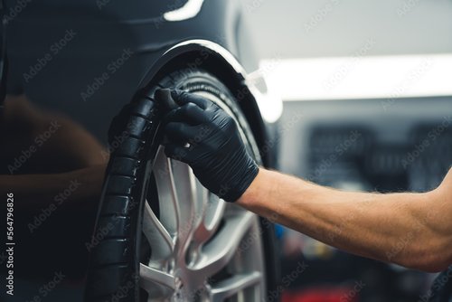 Foto-Fußmatte - Close-up shot of unrecognisable man wearing black glove blackening tires of car using sponge. Professional car detailing in a garage. Horizontal indoor shot. High quality photo (von PoppyPix)
